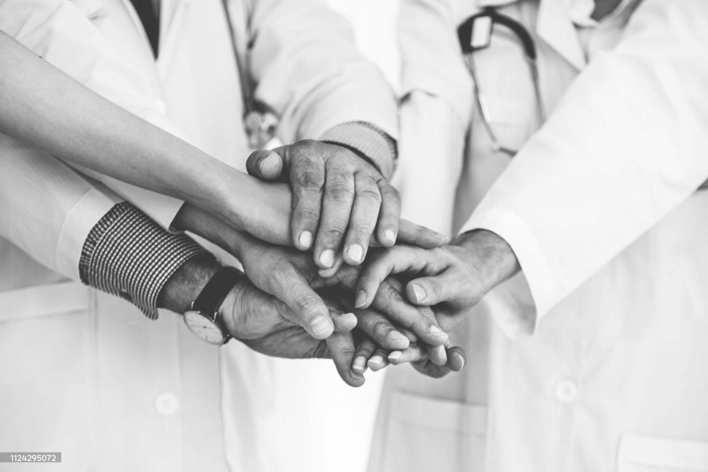 Übereinandergelegte Hände eines medizinischen Teams